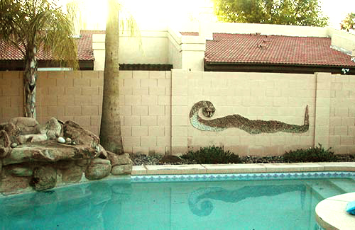 Wall around a pool with a stone  mosaic snake